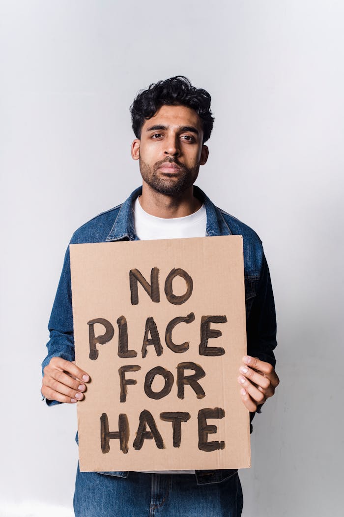 A man holding a 'No Place for Hate' sign advocating against hate and discrimination.